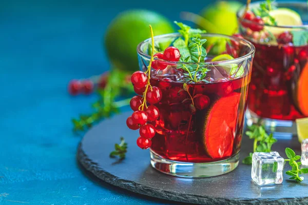 Cold red cocktail with currant, lime, mint, thyme and ice in gla