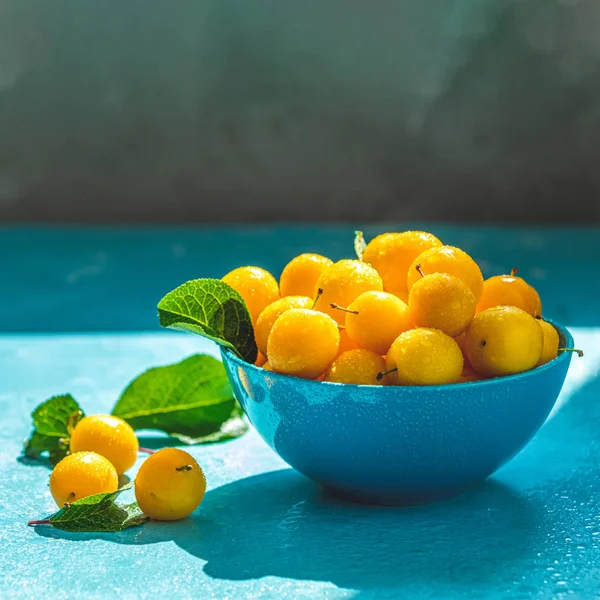 Ciruelas frescas de cereza amarilla dulce con gotas de agua en tazón azul, s —  Fotos de Stock