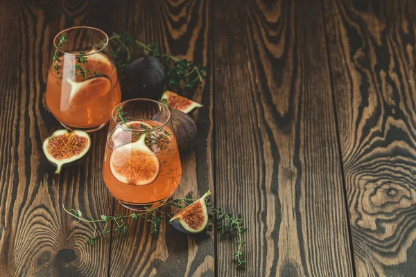 Rosa Cocktail mit Feige, Thymian und Eis im Glas auf dunklem Holzboden — Stockfoto