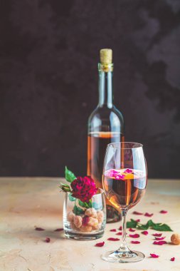 Gül şarabı ve gül şarabı ile servis edilen bir şişe şarap ve bardak.