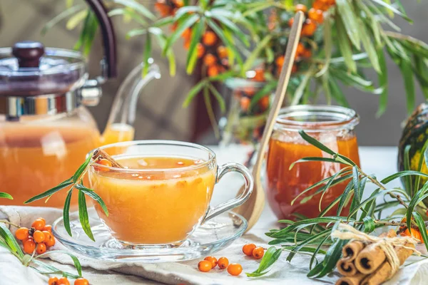 Hot spicy tea with sea buckthorn in glass cup and teapot, select