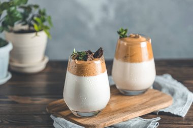 İki bardak Dalgona köpüklü kahve. Kore kahvesi. Kekik ve koyu çikolatayla süslenmiş kahve köpüklü latte espresso. Koyu tahta masa yüzeyi