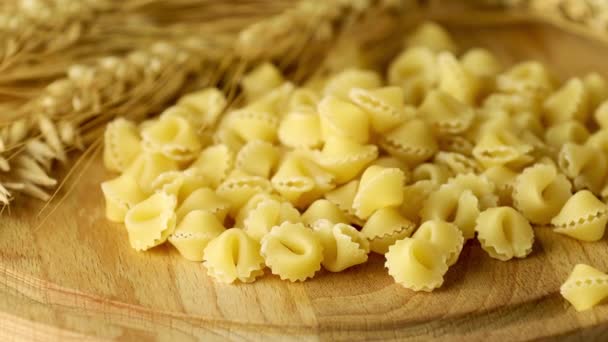 木製のテーブルの上に小麦の耳を持つイタリアの生の未調理パスタのソープ 動画だ 健康的な食事の概念 — ストック動画