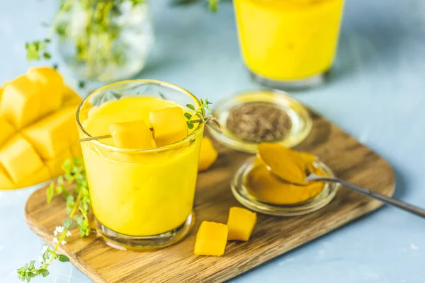 Sarı Hint mangolu yoğurt Mango Lassi ya da zerdeçal ve safranlı smoothie. Sağlıklı probiyotik Hint soğuk yaz içeceği mavi arka planda.