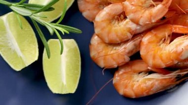 Seramik tabakta maydanoz ve limonla kaynatılmış güzel bir karides. Taze deniz ürünleri, karides kuyruğu pişirmeye hazır. Haşlanmış karides. Yavaş hareket 4k video