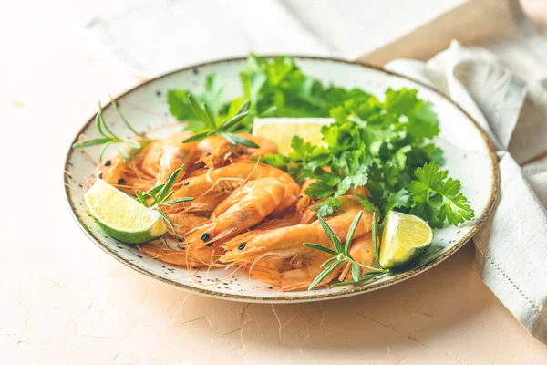 Seramik tabakta kaynatılmış güzel karides maydanoz ve pembe beton masa yüzeyinde limon. Taze deniz ürünleri - karides kuyruğu pişirmeye hazır..