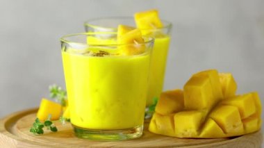 Sarı Hint mangolu yoğurt Mango Lassi ya da zerdeçal ve safranlı smoothie. Sağlıklı probiyotik Hint soğuk yaz içeceği açık gri arka planda yavaşça ilerliyor