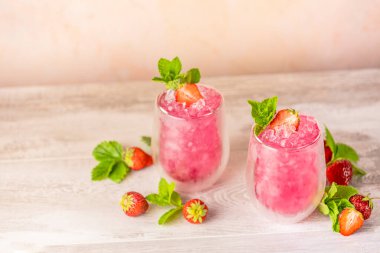 Taze çilek kokteyli. Çilekli ve buzlu taze yaz kokteyli. Açık pembe arka planda bir bardak çilekli soda..