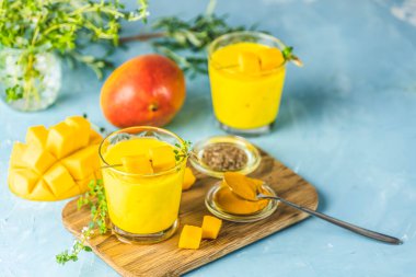 Sarı Hint mangolu yoğurt Mango Lassi ya da zerdeçal ve safranlı smoothie. Sağlıklı probiyotik Hint soğuk yaz içeceği mavi arka planda