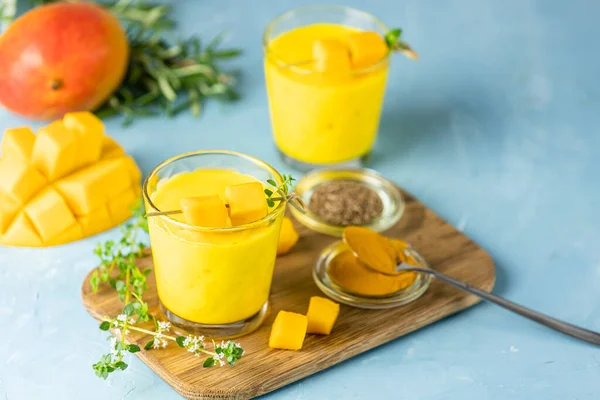 Sarı Hint mangolu yoğurt Mango Lassi ya da zerdeçal ve safranlı smoothie. Sağlıklı probiyotik Hint soğuk yaz içeceği mavi arka planda