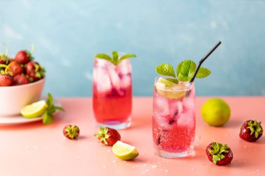 Açık mavi arka planda iki bardak çilekli mojito kokteyli, pembe tahta. Kopyalama alanı, yaz tatili ve parti konsepti