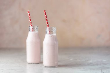 Lezzetli çilekli milkshake şişeleri ya da masada smoothie ve pembe arka plan.