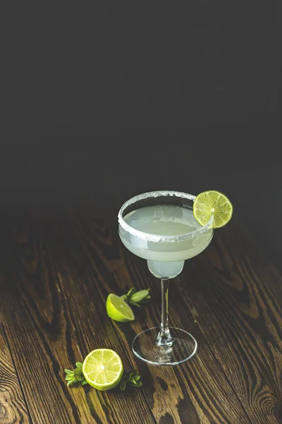 Margarita cocktail with lime and ice on dark wooden background, copy space. Classic Margarita or Daiquiry Cocktail.