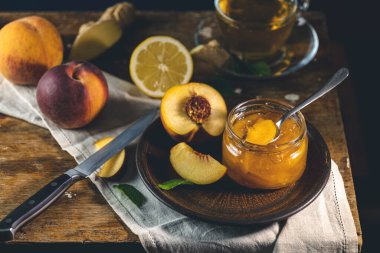 Taze ev yapımı şeftali reçeli kavanoza doluyor. Eski karanlık kırsal sihir tarzı. Güneşli ışık.