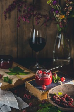 Fresh homemade easy raspberry filling in to the jar. Old dark rustic magic style. Sunny light.	