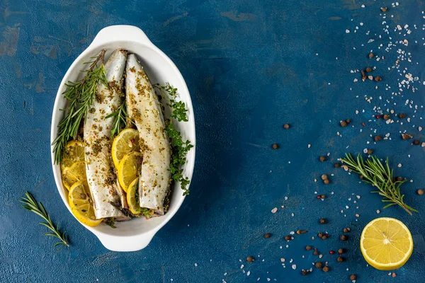 Uskumrular limon, kekik, biberiye ve baharatla servis edilir. Klasik mavi yüzeyde marine edilmiş çiğ balıklar. Deniz ürünleri arka planı.