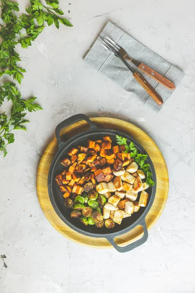 Sağlıklı yiyecekler. Bir kap tavuk eti, kızarmış patates ve Brüksel lahanası. Üst manzara, açık gri beton yüzey, düz uzanma.