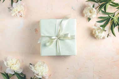 Açık beton masa yüzeyindeki hediye güzel beyaz şakayık çiçeklerini çevreledi. Üst manzara, düz yatak, tebrik kartı..