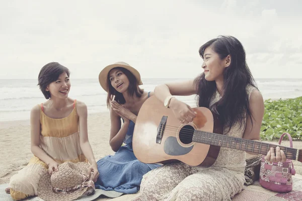 年轻的亚洲女性朋友度假放松弹吉他和海海滩上唱一首歌 — 图库照片