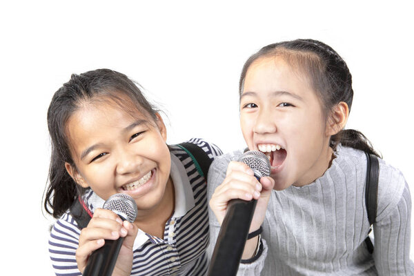 Два весёлых азиатских подростка поют с микрофоном на белом фоне
