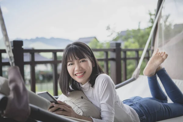 亚洲年轻女子放松与牙齿微笑的脸上的摇篮 — 图库照片