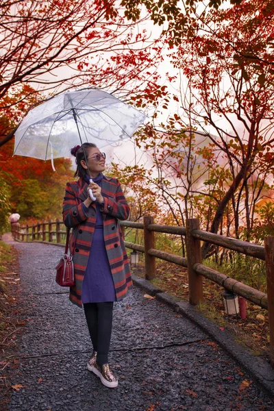happiness asian woman with rain umbrella standing in leaves color change  japan autumn season