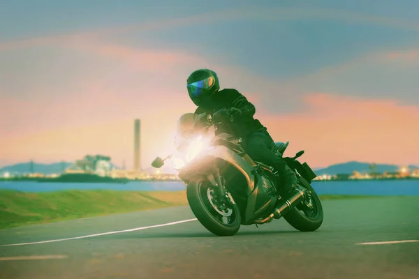 現代人のライフ スタイルと休日の活動と都市の産業シーン使用の美しい照明に対してアスファルトを高速道路でオートバイのツーリング若い男乗馬スポーツ — ストック写真