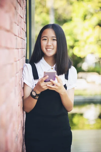 美丽的亚洲青少年牙齿微笑的脸使用智能手机在手 — 图库照片