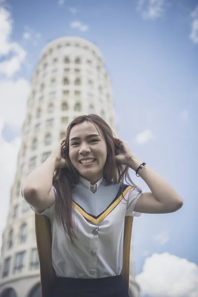 开朗的亚洲年轻女子穿着大学制服摆出街头时尚风格 — 图库照片
