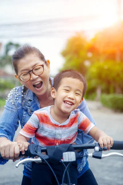 母笑みを浮かべて顔幸福感情を自転車に乗ってアジアの子供の肖像 — ストック写真