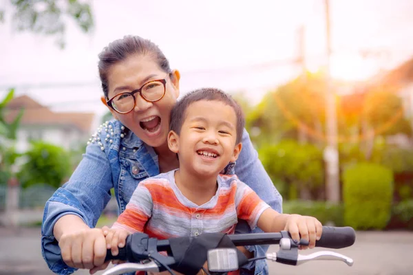 母笑みを浮かべて顔幸福感情を自転車に乗ってアジアの子供の肖像 — ストック写真