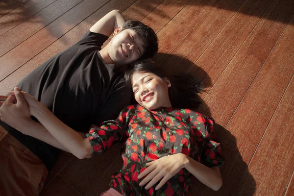 亚洲年轻的男人和女人躺在木地板上幸福的脸 — 图库照片