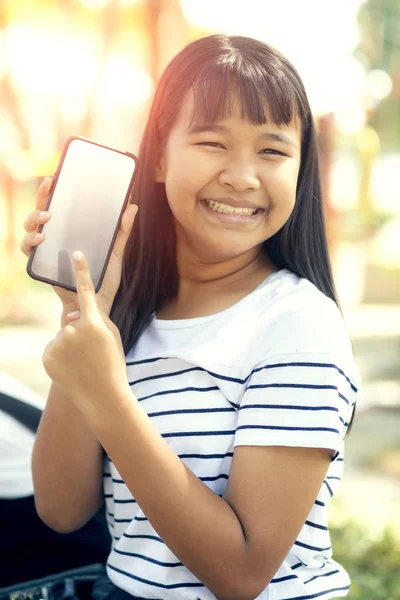 asian teenager show white screen of  smart phone screen  and toothy smiling face happiness emotion