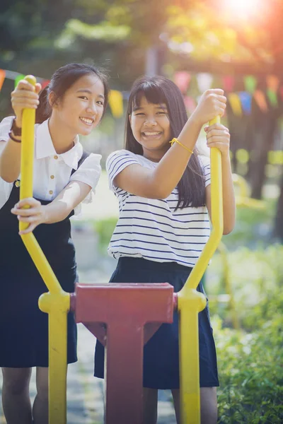 两个开朗的亚洲青少年在公共操场上的牙齿般的笑脸 — 图库照片