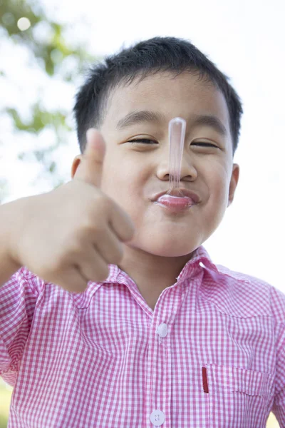 Lustiges Gesicht asiatischer Kinder, die Milcheis im Teelöffel essen — Stockfoto