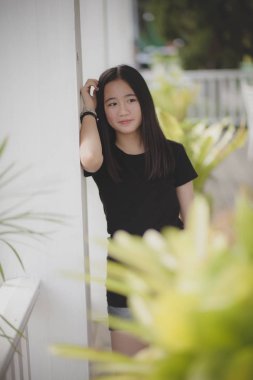 Asyalı genç ayakta duruyor ve modellik yapıyor.