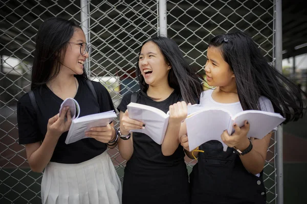 Asiático adolescente segurando escola livro e rindo com felicidade e — Fotografia de Stock