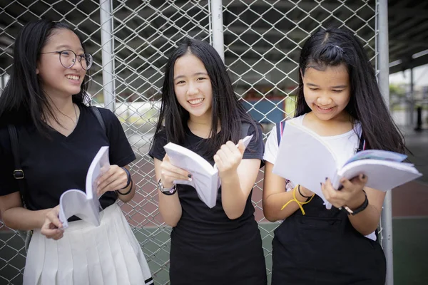 Asiático adolescente segurando escola livro e rindo com felicidade e — Fotografia de Stock