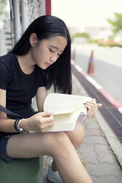 Aziatische tiener lezing boek Schoolstraat kant — Stockfoto