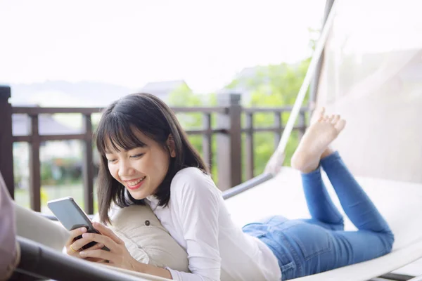 Asiatische jüngere Frau toothy lächelnd mit Glück halten smart — Stockfoto
