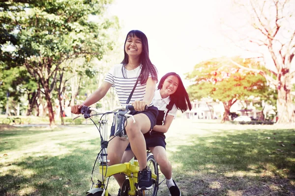 Cheerful asian teenager riding bicycle in pulbic park — Stock Photo, Image