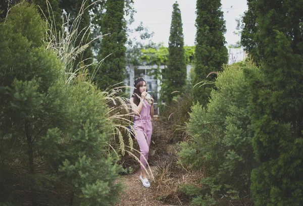 Mladší žena pije chladný nápoj v zeleném parku — Stock fotografie