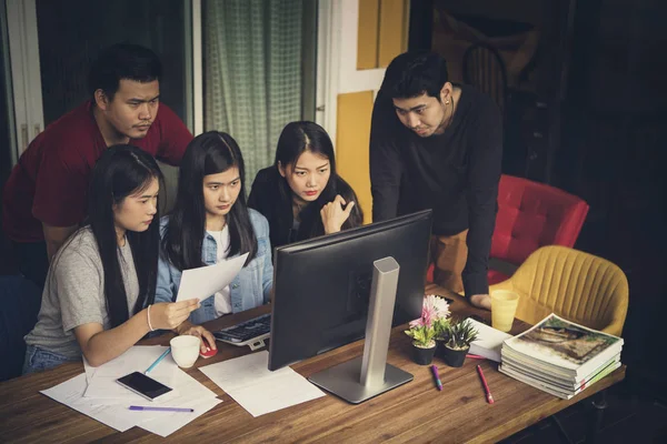 Азіатська позаштатна команда шукає офісний комп'ютер з серйозно f — стокове фото