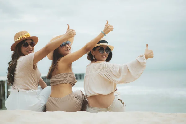 Three woman wearing straw hat  sitting on vacation beach  rising — Stock Photo, Image