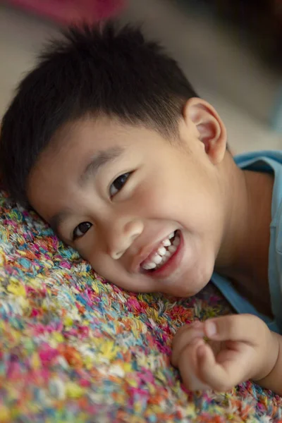 Dentino sorridente faccia di asiatico bambino sdraiato su pavimento — Foto Stock