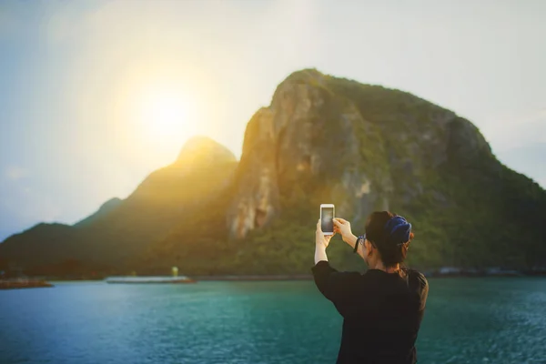 Mujer tomando una foto de la salida del sol y la costa del mar por teléfono inteligente — Foto de Stock