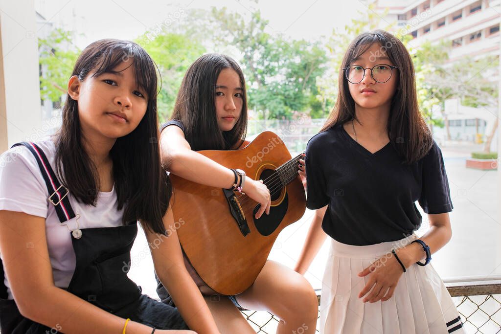 three asian teenager playing guitar like a band