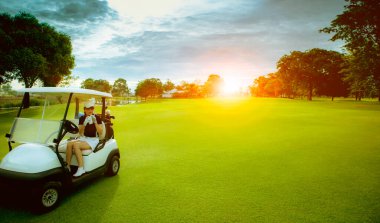 Kadın golfçü golf sahasında serin su içiyor.