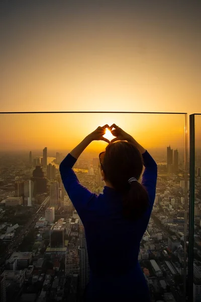Kadın Yüksek Bir Binanın Çatısında Duruyor Kalp Şeklinde Parmak Yapıyor — Stok fotoğraf