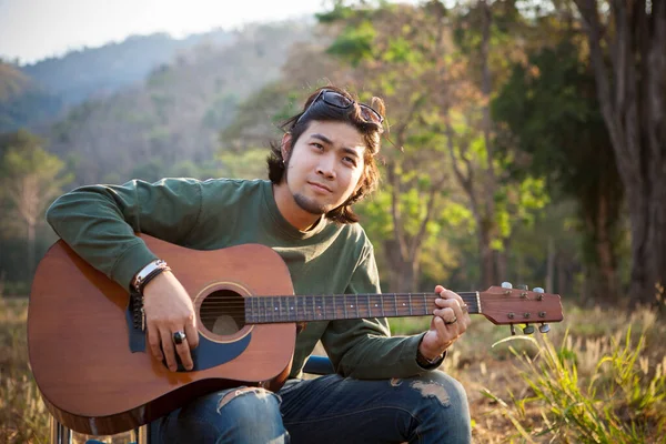 亚洲人在自然领域弹吉他 — 图库照片